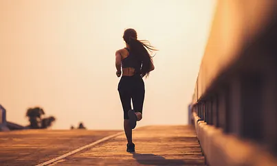 Eine Läuferin joggt auf dem Gehweg