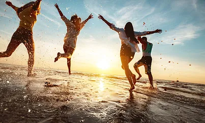 Fröhliche Menschen laufen glücklich über Strand